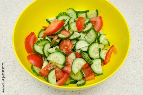 vegetable salad of fresh tomatoes and cucumbers in a yellow salad bowl