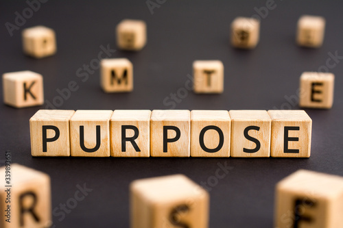 Purpose - word from wooden blocks with letters, target objective goal purpose concept, random letters around white background