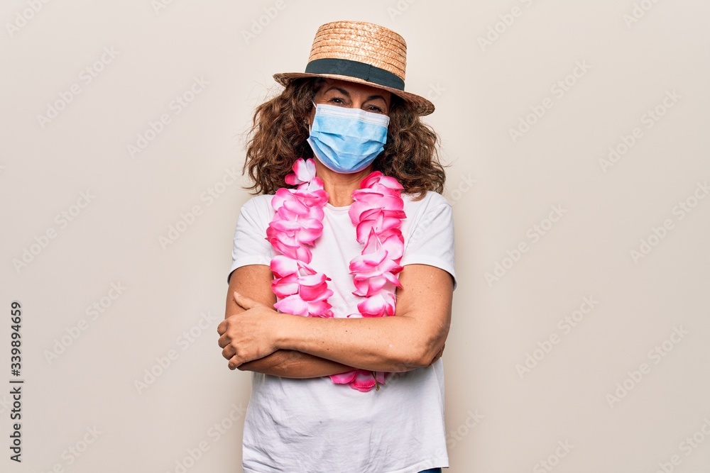 Middle age tourist woman wearing coronavirus protection mask and summer hat on vacation happy face smiling with crossed arms looking at the camera. Positive person. Middle age tourist woman wearing coronavirus protection mask and summer hat on vacation happy face smiling with crossed arms looking at the camera. Positive person.