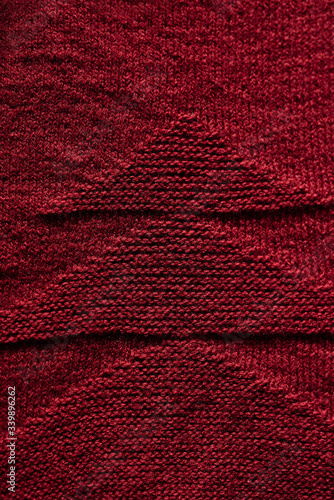 Knitted fabric with pattern, red woolen threads, knitted texture. Macro, top view. .Fragment from knitwear, knitted sweater, pattern ornament