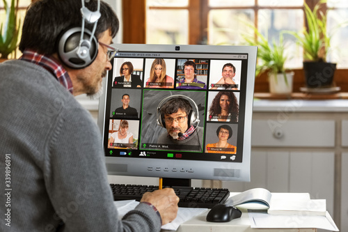 фотографія A moderator manages a video conference from his home office