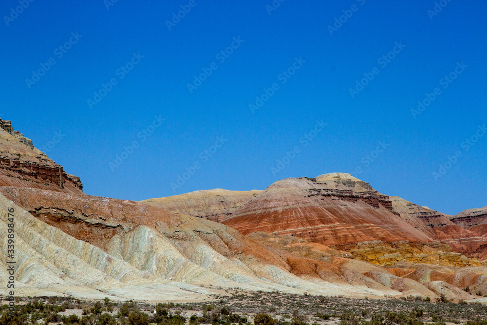 Colored, layered Aktau mountains in Kazakhstan among saxaul bushes. Above is a space for text.