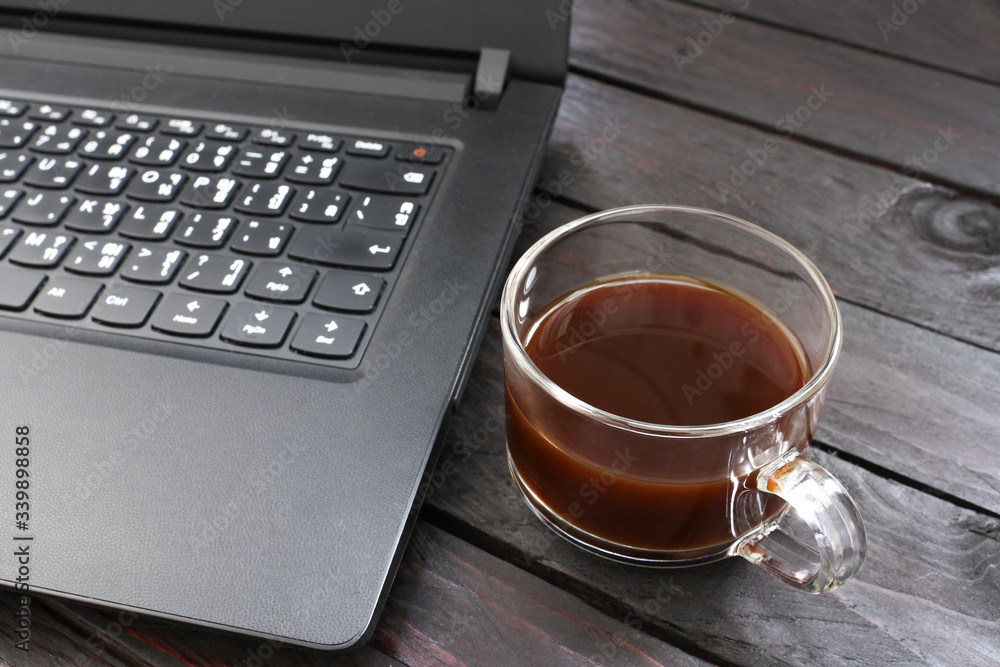 ฺBlack coffee Put aside laptop on a wooden table break during working hours in office ฺBlack coffee Put aside laptop on a wooden table break during working hours in office