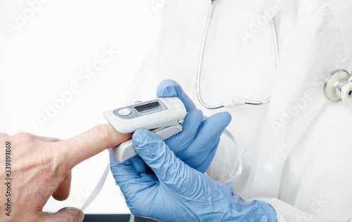 Doctor using pulse oximeter to check oxygen saturation of a person tracking coronavirus symptoms photo