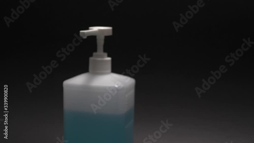 Moving up away above sanitizer on black background. Slow motion shot with antiseptic.