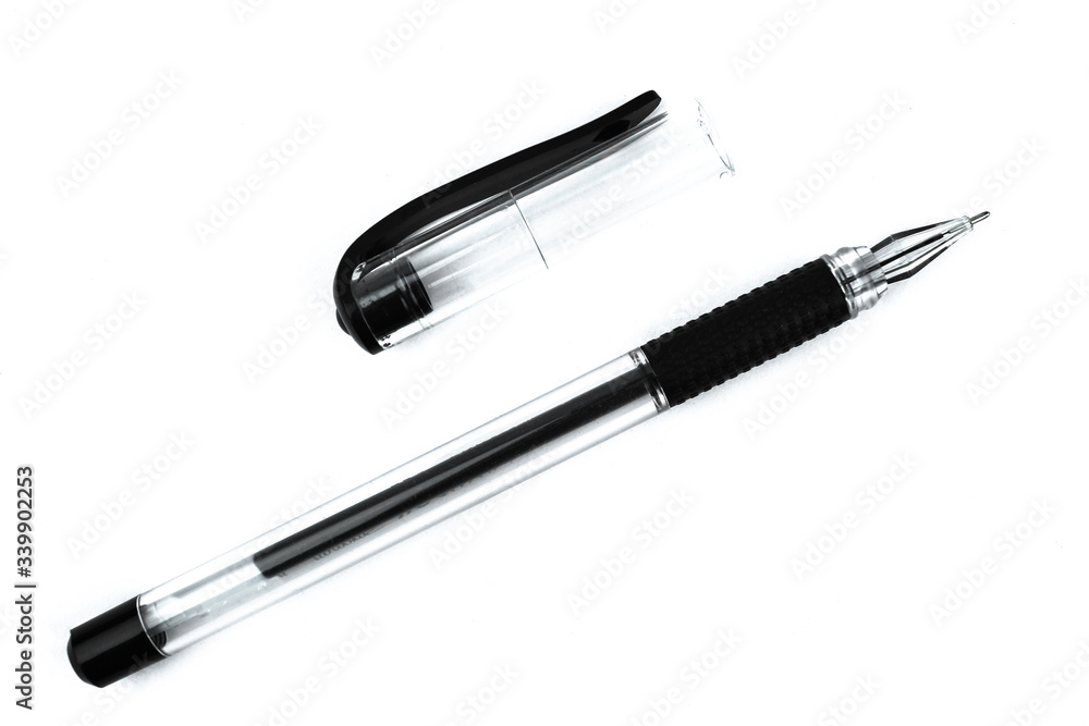 A black colored ball point pen and its cap scattered on top of a white background A black colored ball point pen and its cap scattered on top of a white background