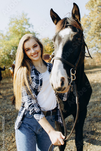 Portrait of beautiful young woman smiling and standing by horse in countryside.  © elomo