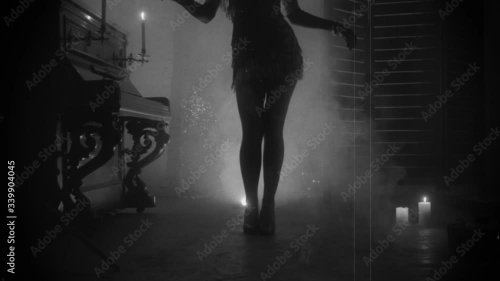 Old film style grain added. black and white color dark mysterious female silhouette. short vintage dress waving fly in motion. retro woman dancer dances twenties style. room full smoke. sexy lond legs