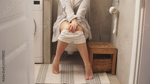 Woman sitting on toilet in the bathroom. Lady has urinary bladder problem or constipation.