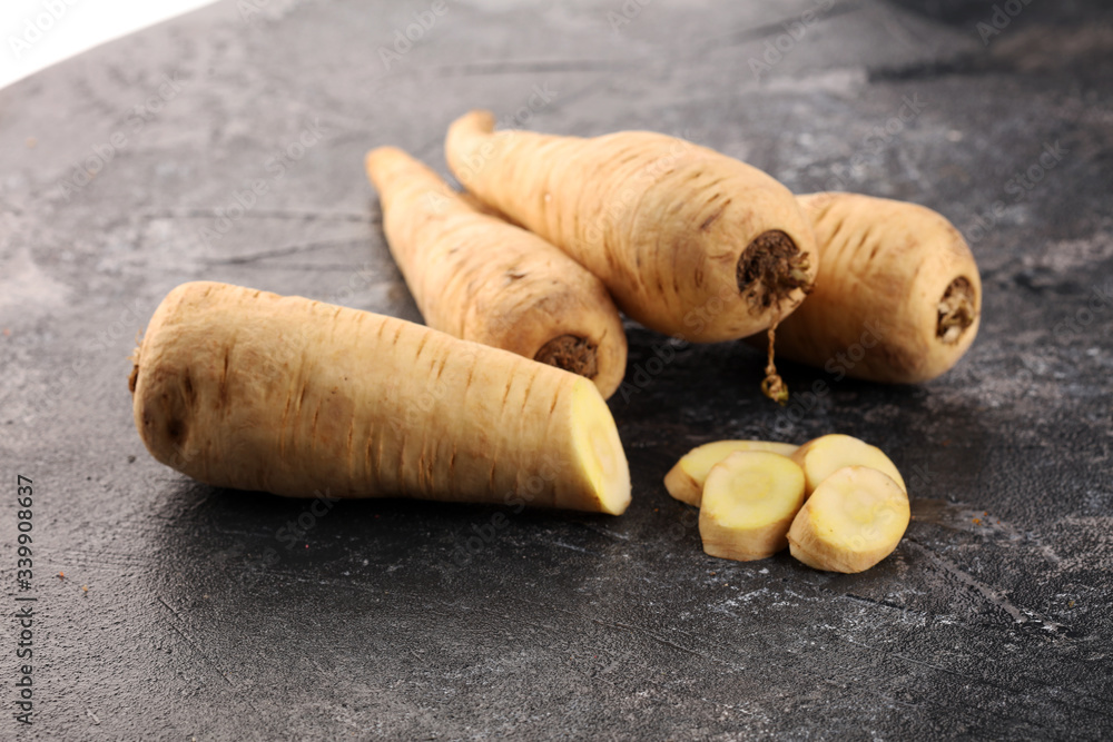 Parsnip root and slices on rustic background. Fresh raw organic parsnip