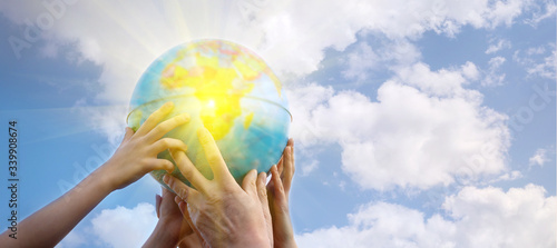 The world is in your hands. Concept of world environment day. Human hands hold the globe against a blue cloudy sky. Selective focus  banner  copy space.