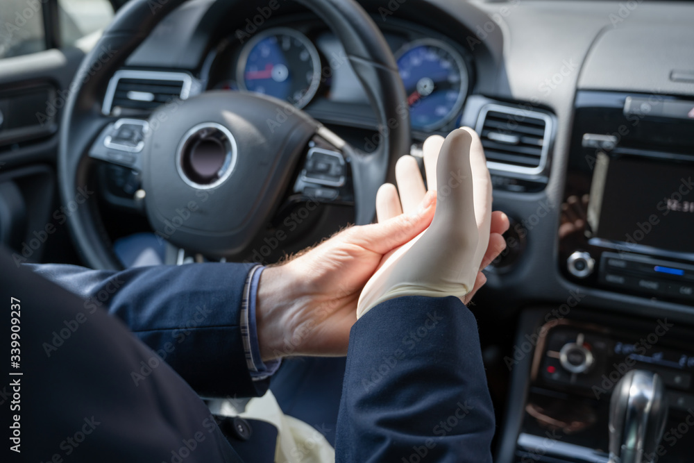 Middle age businessman in blue suit puts on rubber gloves for protect himself from bacteria and virus while driving a car. Coronavirus. Pandemic Middle age businessman in blue suit puts on rubber gloves for protect himself from bacteria and virus while driving a car. Coronavirus. Pandemic