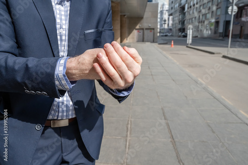 Businessman in a blue suit using small portable antibacterial sanitizer applying antiseptic for washing hand on the street. protection from bacteria and virus. hygienic gel. Coronavirus. photo