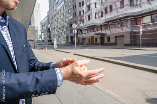 Businessman in a blue suit using small portable antibacterial sanitizer applying antiseptic for washing hand on the street. protection from bacteria and virus. hygienic gel. Coronavirus. photo