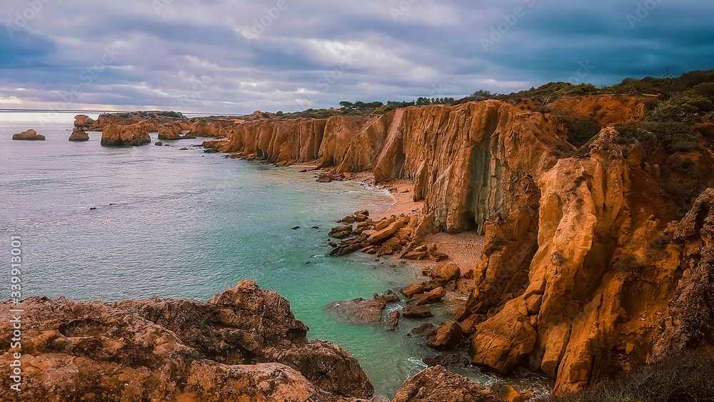 Beautiful view on Praia dos Arrifes on Algarve coast near Albufeira, Portugal. Panoramic view on calm turquoise ocean water, high rock cliffs and small empty beach. Tourism concept.