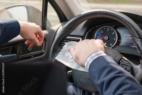 Middle age businessman in a blue suit cleaning steering wheel of a car using antivirus antibacterial wet wipe (napkin) for protect himself from bacteria and virus © flowertiare