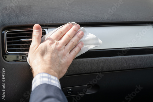 Middle age businessman in a blue suit cleaning front dashboard of a car using antivirus antibacterial wet wipe (napkin) for protect himself from bacteria and virus