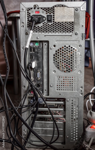 The rear view of the computer with connectors and black wires close up. Vertical photo