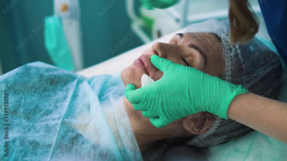 CU shot: middle aged woman client undergoes lips augmentation procedure injection made by skilled master in modern beauty clinic closeup CU shot: middle aged woman client undergoes lips augmentation procedure injection made by skilled master in modern beauty clinic closeup