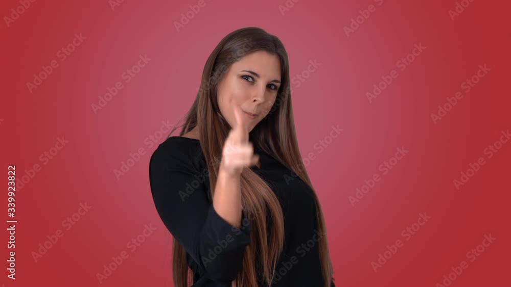 A seductive brunette shooting at camera with her fingers on a red background A seductive brunette shooting at camera with her fingers on a red background
