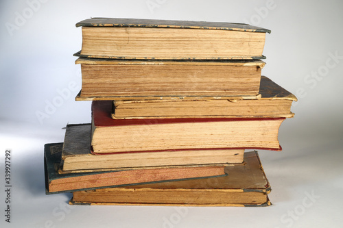 Composition of old books, with yellowed and ruined pages. Light background.