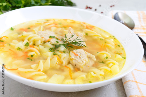 Dietary chicken soup with fusilli in a white bowl on a light background