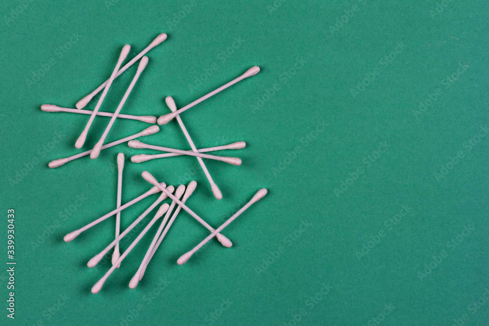 cotton swabs are scattered on a green background close up view from above with a copy space cotton swabs are scattered on a green background close up view from above with a copy space