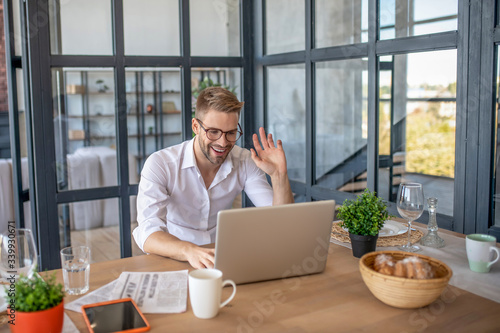 Young handsome man in white shirt greeting his colleague online