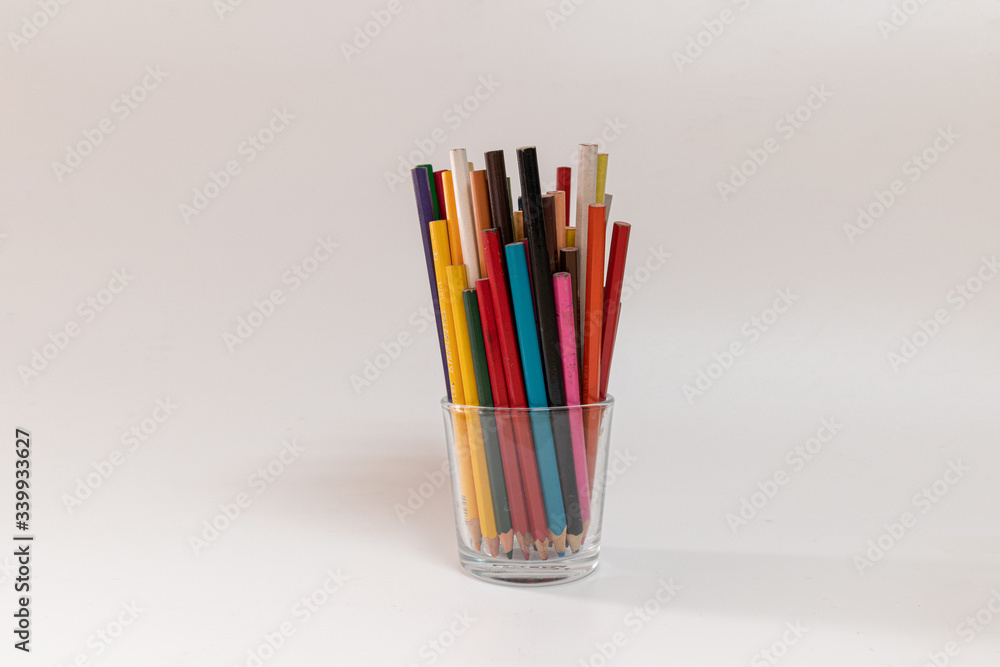 Fototapeta premium Glass pot full of colored pencils for the children to draw and make paintings