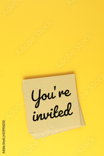 Paper sheet with text "you're invited" on yellow background