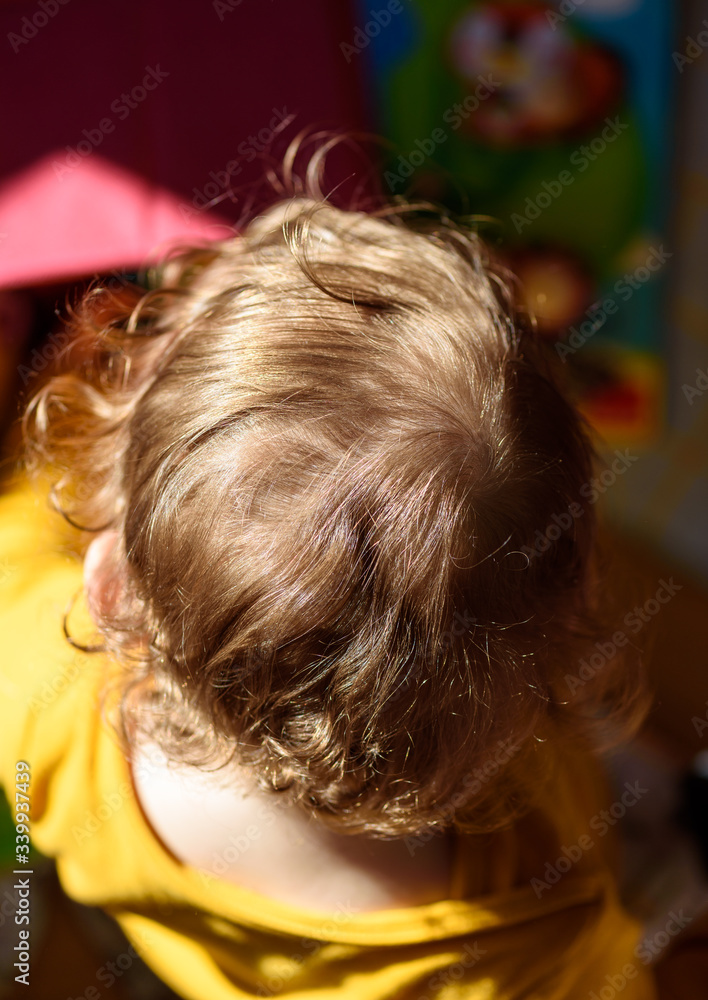 Top view of a strawberry blonde curly-haired caucasian child illuminated by the sunlight. Top view of a strawberry blonde curly-haired caucasian child illuminated by the sunlight.