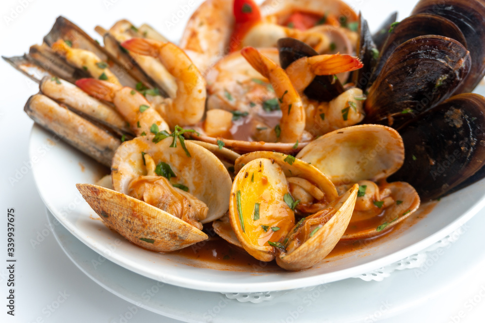 Sauteed shellfish and seafood in a white plate on a white background Sauteed shellfish and seafood in a white plate on a white background