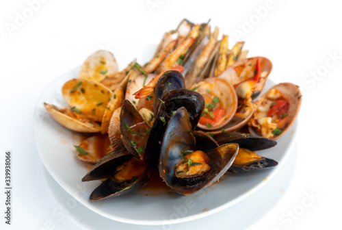 Sauteed shellfish and seafood in a white plate on a white background