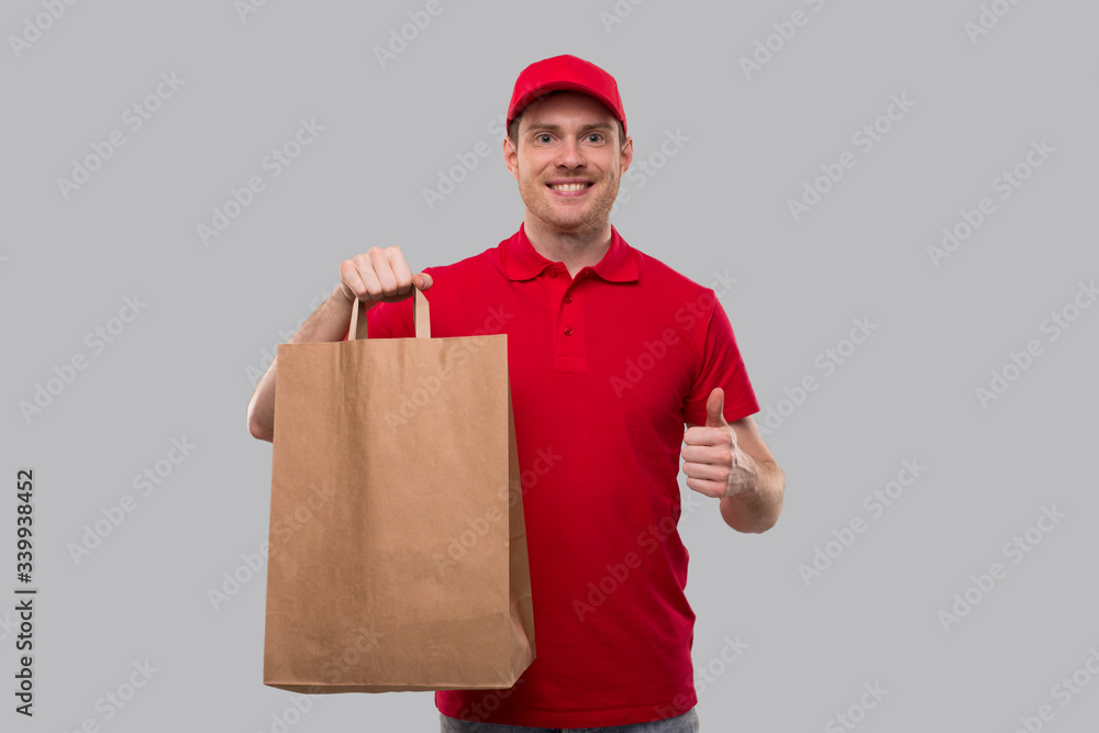 Delivery Man With Paper Bag in Hands Showing Thumb Up. Red Tshirt Delivery Boy. Home Food Delivery.