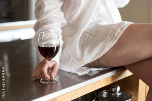 Obraz na płótnie beautiful woman dressed in a man's shirt is drinking wine in the kitchen w salonie