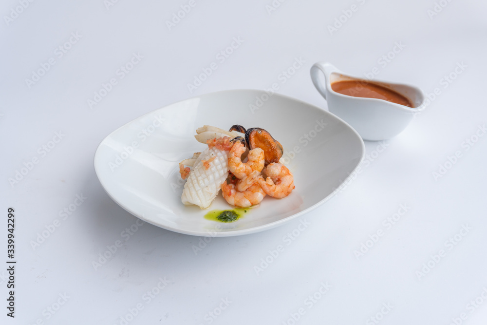 Fancy FISH AND SEAFOOD with soup on a white plate with a white background Fancy FISH AND SEAFOOD with soup on a white plate with a white background