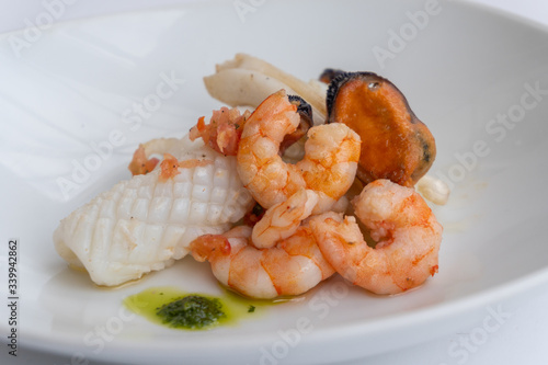 Fancy FISH AND SEAFOOD with soup on a white plate with a white background