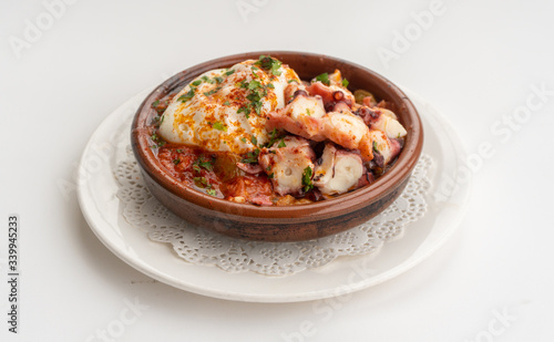 Octopus ratatouille with an egg in a clay pot dish with a white background