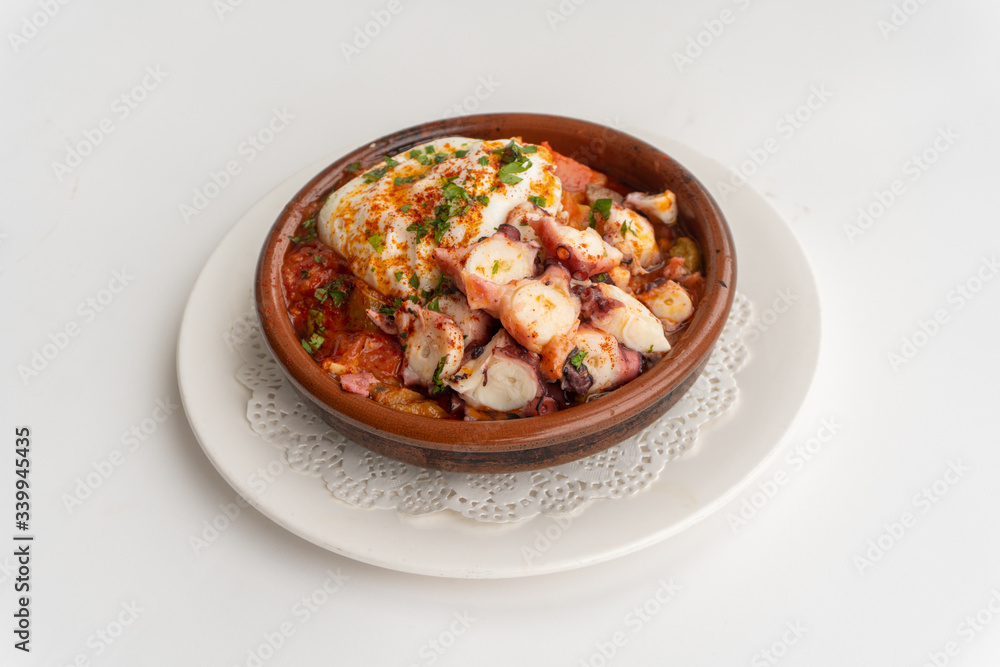 Octopus ratatouille with an egg in a clay pot dish with a white background Octopus ratatouille with an egg in a clay pot dish with a white background