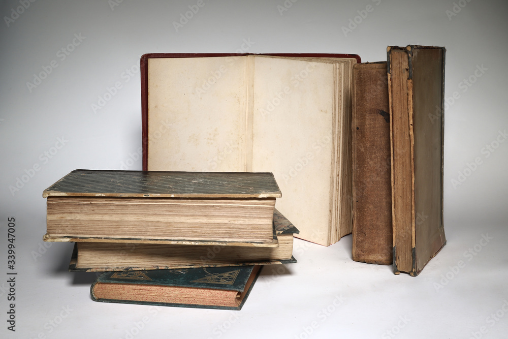 Composition of old books, with yellowed and ruined pages. Light background.