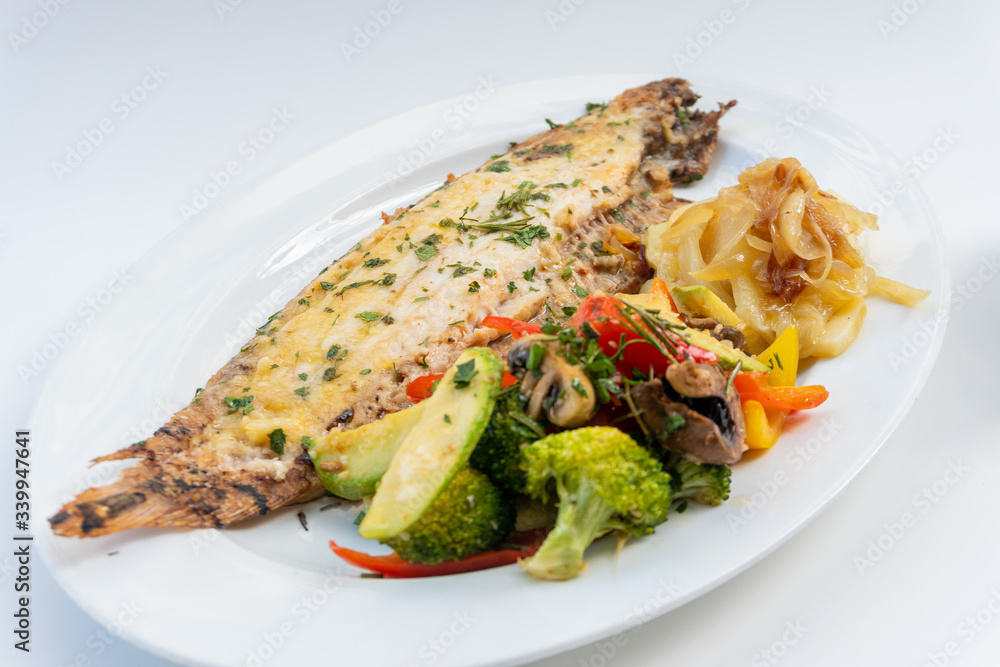 Sole meunière fish with grilled vegetables and caramelized onions on a white plate with white background. LENGUADO MENIER Sole meunière fish with grilled vegetables and caramelized onions on a white plate with white background. LENGUADO MENIER