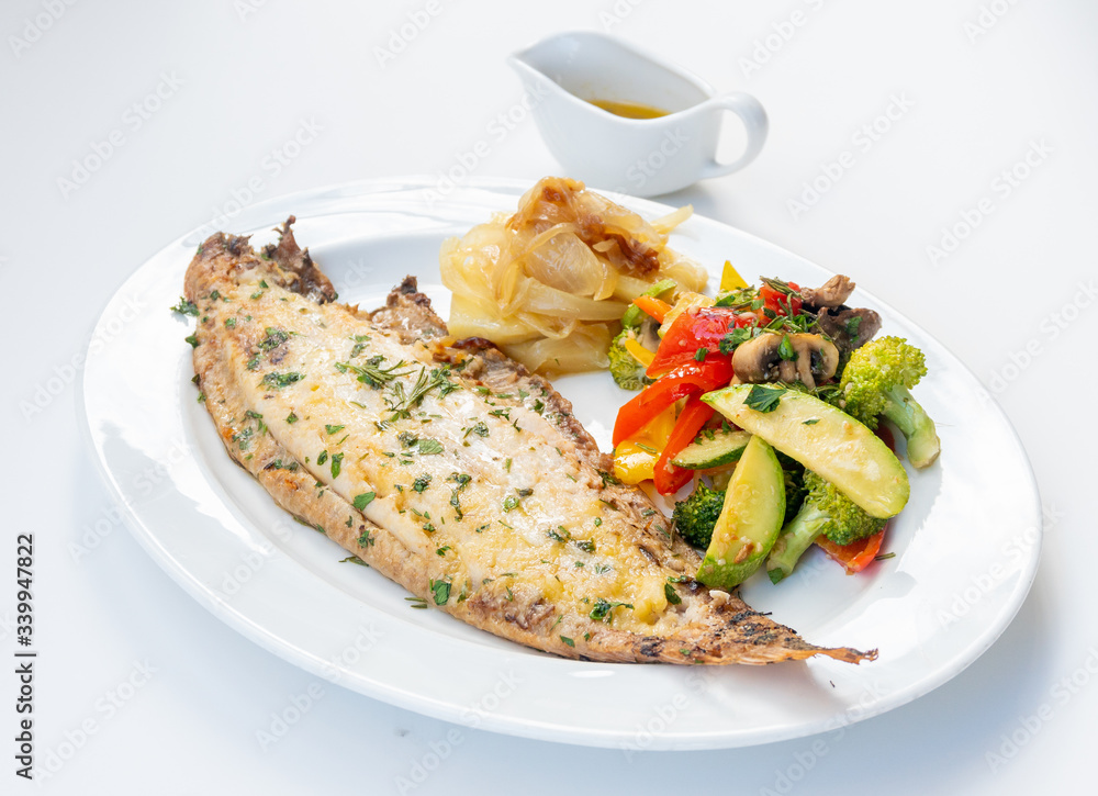 Sole meunière fish with grilled vegetables and caramelized onions on a white plate with white background. LENGUADO MENIER Sole meunière fish with grilled vegetables and caramelized onions on a white plate with white background. LENGUADO MENIER