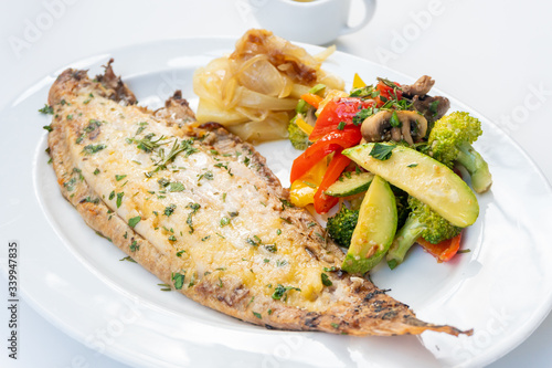Photos Sole meunière fish with grilled vegetables and caramelized onions on a white plate with white background