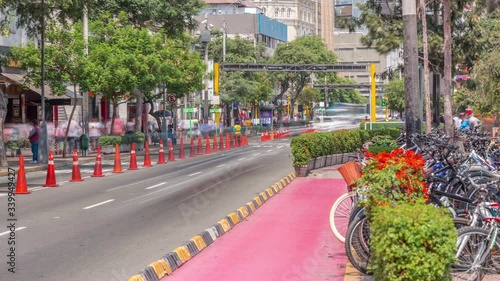 Red cycling track in the Jose Larco avenue and bicycle parking timelapse in Miraflores, Lima Peru. Central park on the right side and traffic on the street