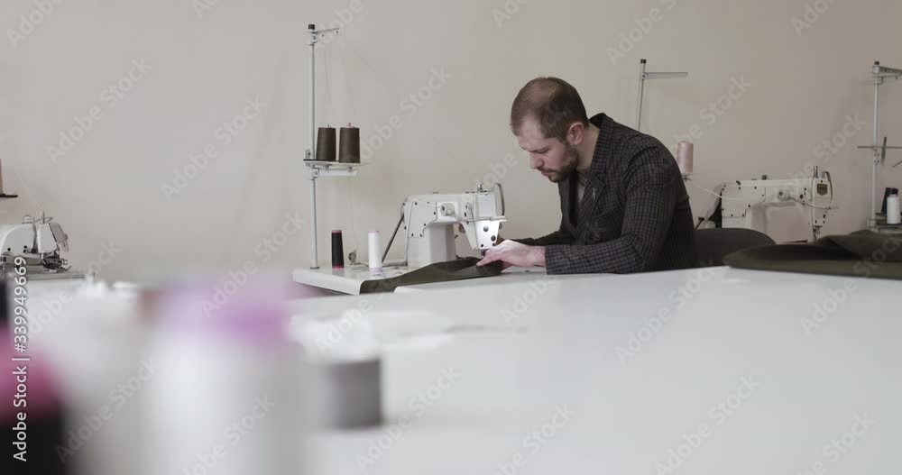 The tailor using the sewing machine to sew a clothes in atelier The tailor using the sewing machine to sew a clothes in atelier