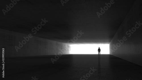 A man standing in the end of an empty dark tunnel photo