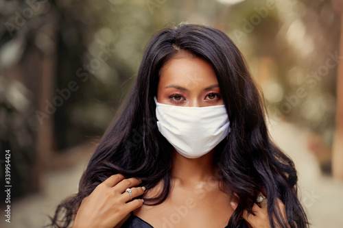 Portrait of beautiful Asian woman wearing surgical face mask protection against virus. Fashion Asian model with white medical mask outdoor