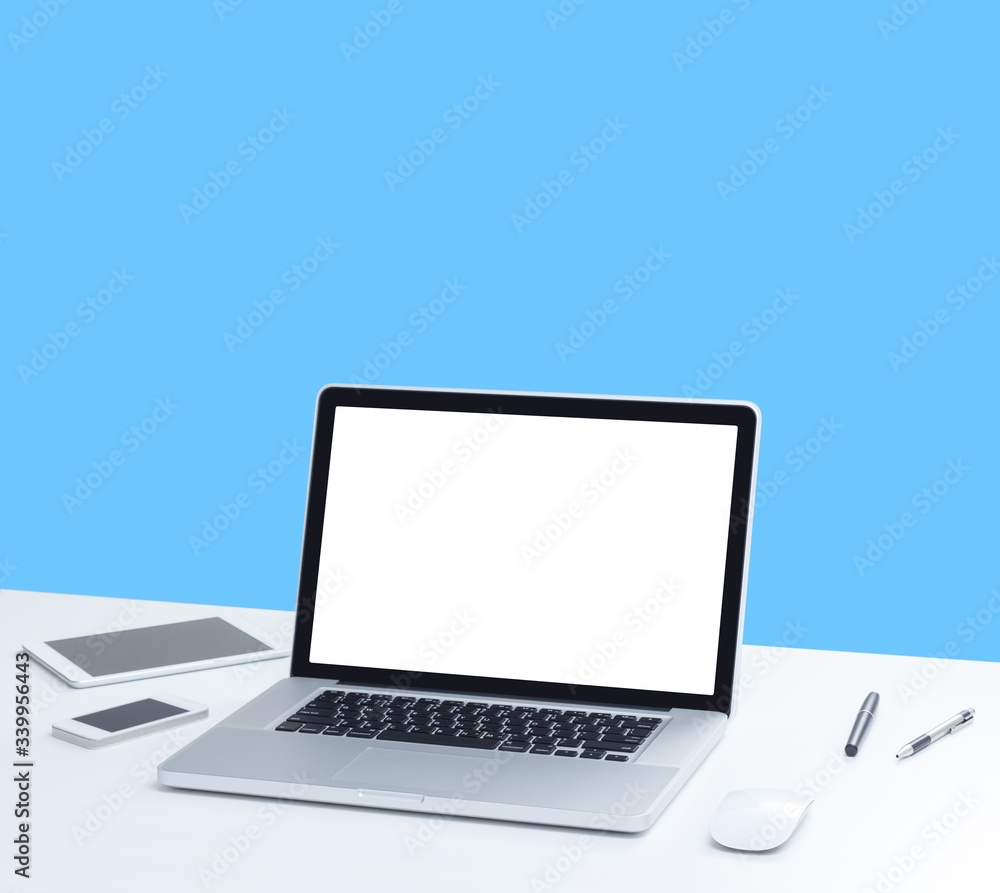 Fototapeta premium Laptop computer on desk with isolated screen for mockup on blue background. business and technology concept