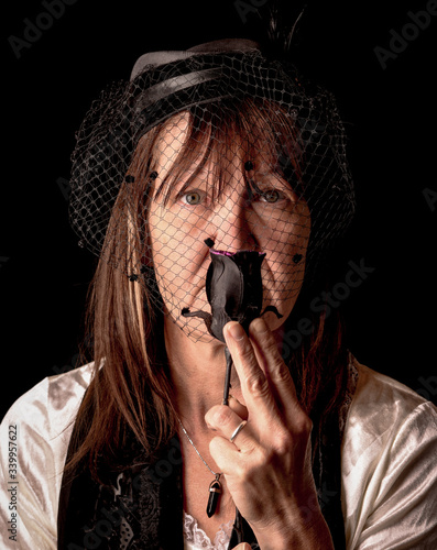 woman with black veil smelling a dead black rose in mourning