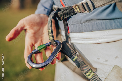 Climbing carabiner cliped or connected to a climbing harness. Climber wearing a harness with biner attached to it. Rock climbing equipment in detail close up photo. photo